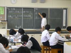 スライド式の黒板をe-黒板の前に移動させて授業を行っている場面。 